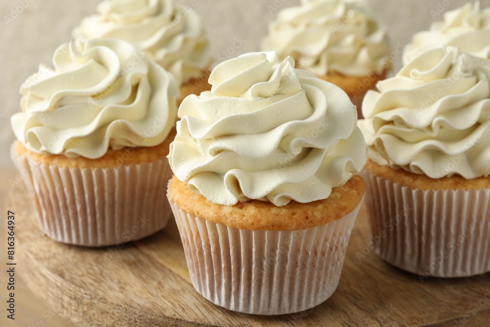Tasty vanilla cupcakes with cream on table, closeup Tasty vanilla cupcakes with cream on table, closeup