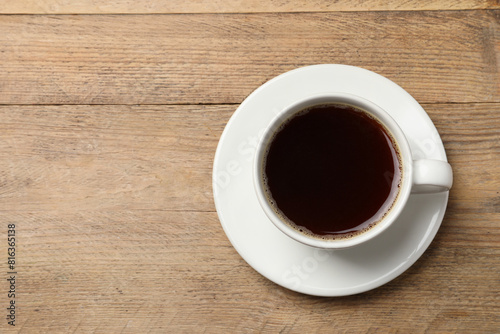 Cup of aromatic coffee on wooden table, top view. Space for text