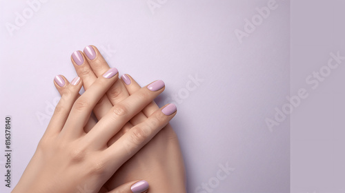 Elegant hands with manicured nails painted in a soft purple shade  isolated on a light purple background.