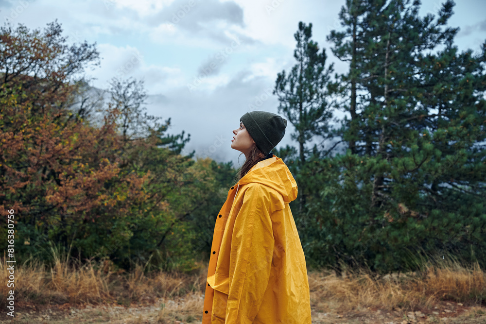 A woman in a yellow raincoat enjoying a peaceful moment surrounded by nature and trees in the field during a rainy day A woman in a yellow raincoat enjoying a peaceful moment surrounded by nature and trees in the field during a rainy day