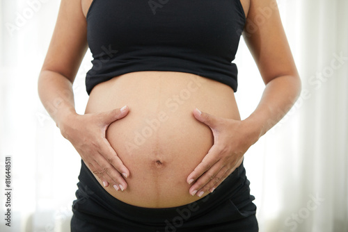 closeup pregnant woman holding hands on stomach
