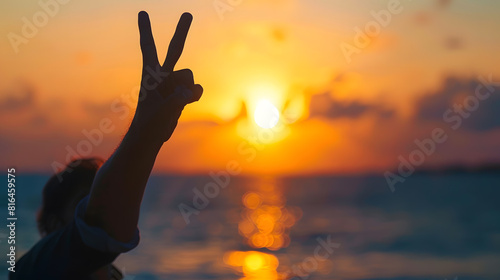 A tranquil silhouette of anonymous person making peace signs with the backdrop of a glowing sunset at sea : Generative AI