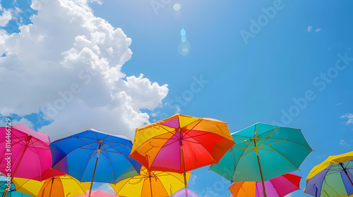 Colorful beach umbrellas against blue sky background, summer vacation concept. Rainbow color sun umbrella for shading from the sunshine