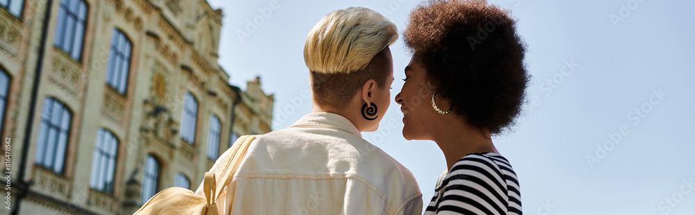 Two stylish black women share a tender kiss in front of a university building, showcasing love and diversity. Two stylish black women share a tender kiss in front of a university building, showcasing love and diversity.