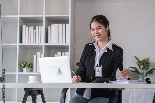 Accountant sitting with financial documents, using laptop, calculating financial and tax figures for company on table in office