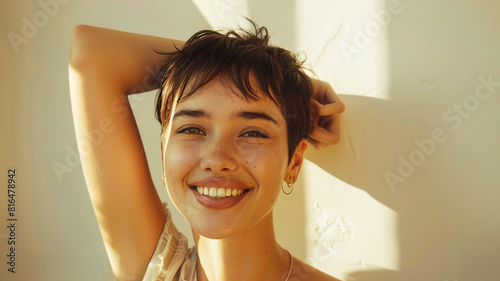 beautiful cute smiling young brunette woman with short hair against light wall in rays of sunlight