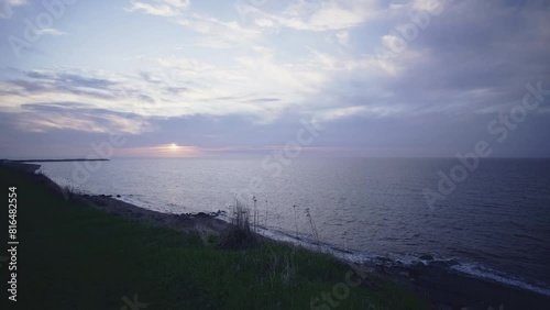 Pale cloudy violet sunset time lapse on saint-laurent river shore grass hill
