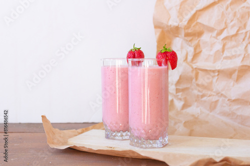 Strawberry fresh pink berry smoothie in two glasses on wooden table