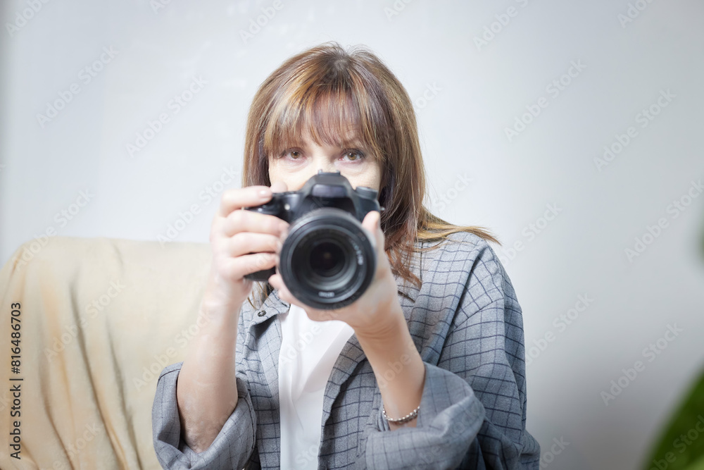 Senior old elderly woman with black camera with a large lens indoors in the studio. A professional photographer. Age Hobby Senior old elderly woman with black camera with a large lens indoors in the studio. A professional photographer. Age Hobby