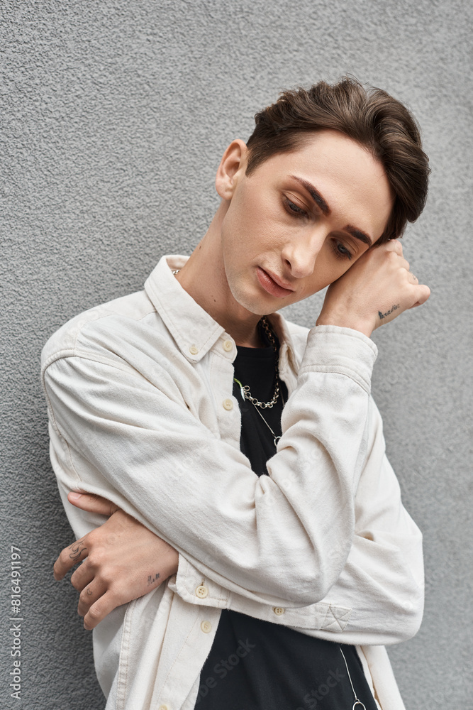 A young man in stylish attire leans against a wall, exuding a sense of rebellion and contemplation. A young man in stylish attire leans against a wall, exuding a sense of rebellion and contemplation.