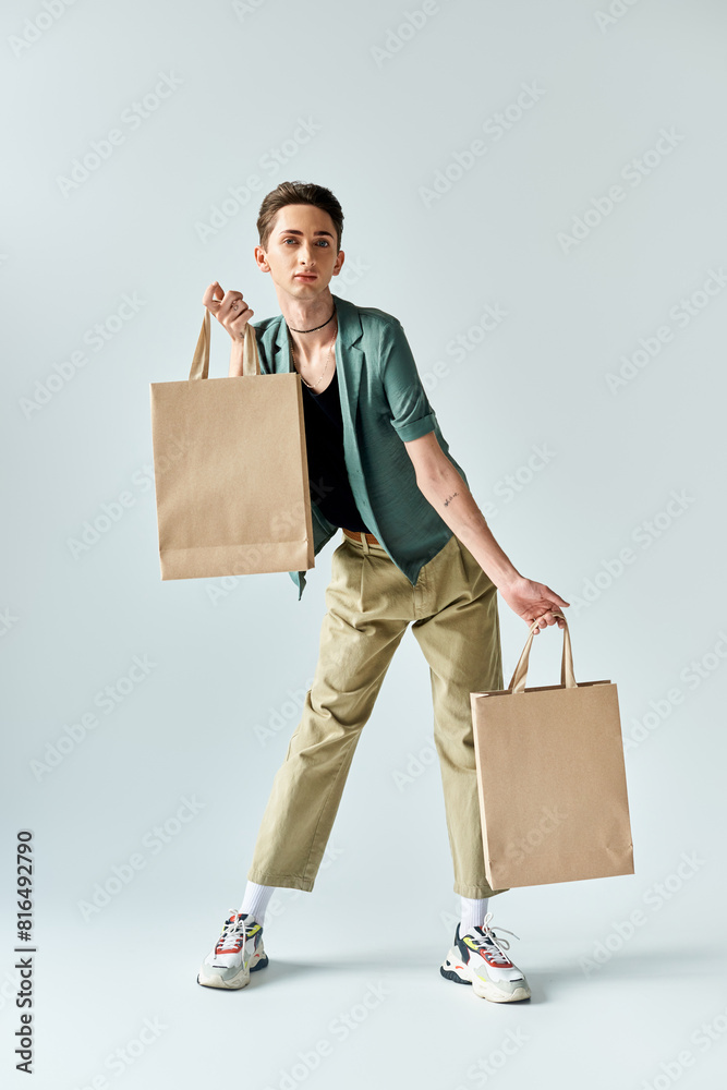 A young queer person proudly holds shopping bags against a white background. A young queer person proudly holds shopping bags against a white background.