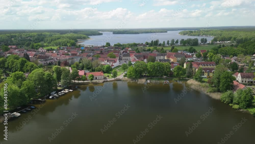 A picturesque aerial view of a charming town nestled on the shores of a tranquil lake. The town's red-roofed houses and lush greenery create a serene and inviting atmosphere. A picturesque aerial view of a charming town nestled on the shores of a tranquil lake. The town's red-roofed houses and lush greenery create a serene and inviting atmosphere.