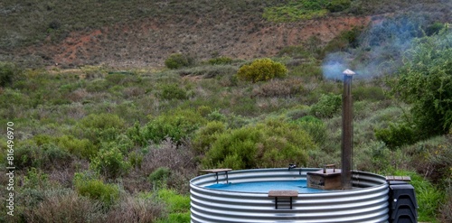 An outdoor hot tub made from metal roof sheets water warmed by a wood fire
