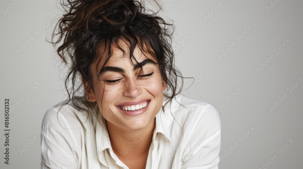  A woman happily smiles with closed eyes, her untidy topknot bouncing in the wind