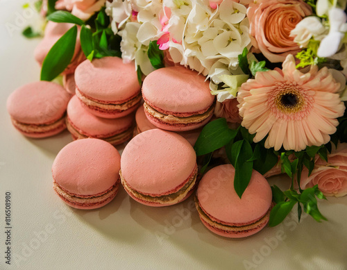 Sweet yellow macarons or macaroons and white daisies flowers on wooden table