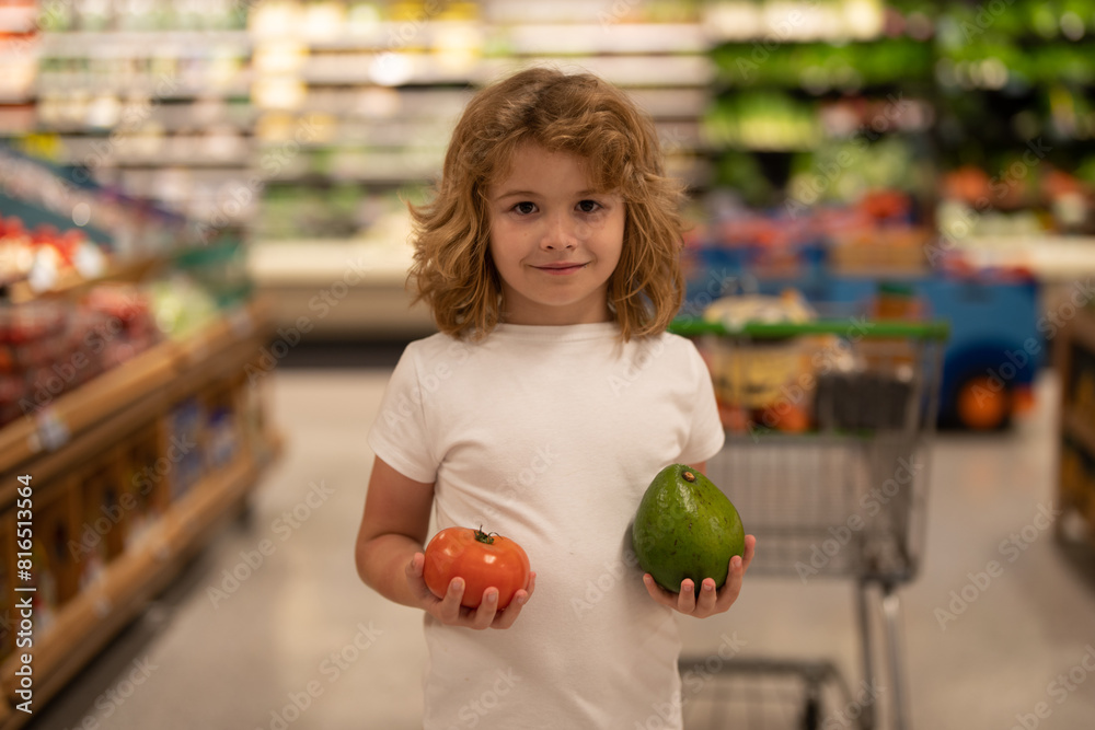 Fototapeta premium Child choosing vegetables in food store. Kids in food market. Sales, discounts in food market store and shopping. Cute boy in market hold vegetables and fruits. Child shopping in market store.