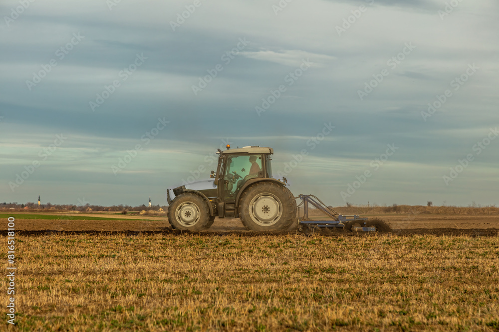 Landscape view of a farmer plowing fertile fields under a vast sky Landscape view of a farmer plowing fertile fields under a vast sky