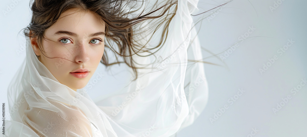 A beautiful young woman with green eyes, wearing a white scarf, with a background suitable for copy space.