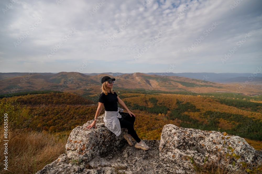 Fototapeta premium woman on mountain peak looking in beautiful mountain valley in autumn. Landscape with sporty young woman, blu sky in fall. Hiking. Nature