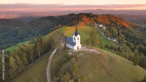 Aerial view of a colourful autumn sunset at Church of Saint Jacob (Sveti Jakob) in Medvode. Snowcapped mountains with the Karawanks, the Julian Alps and the Triglav, Medvode, Ljubljana, Slovenia photo