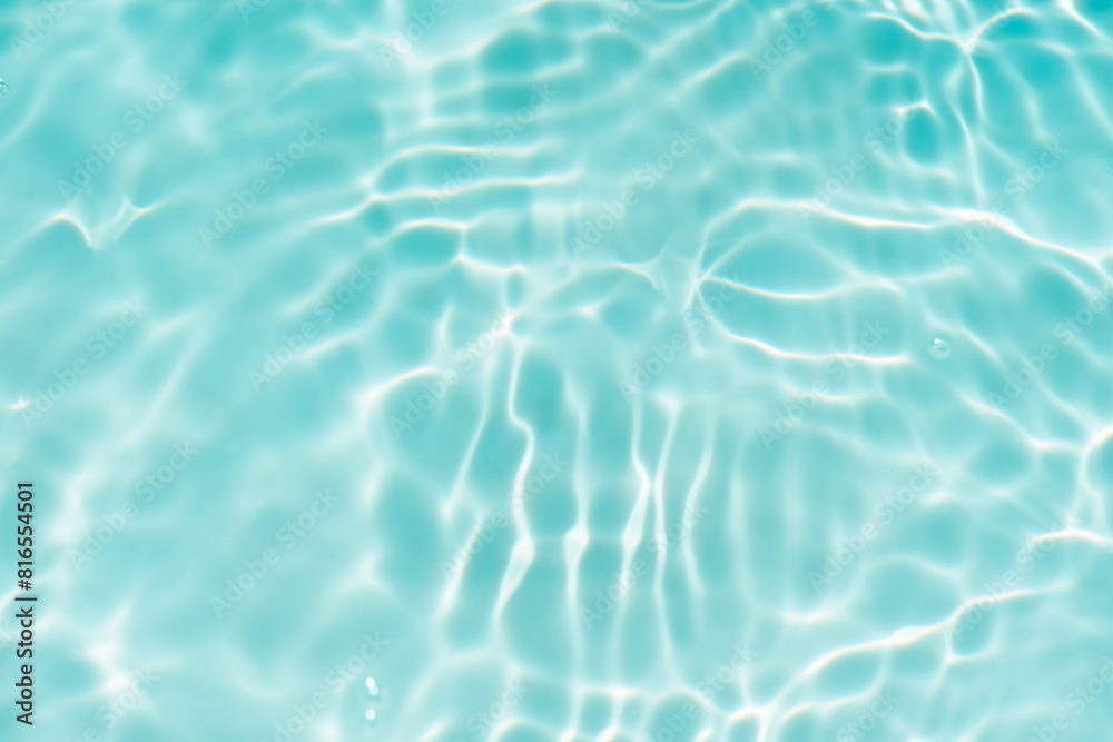 Blue water with ripples on the surface. Defocus blurred transparent blue colored clear calm water surface texture with splashes and bubbles. Water waves with shining pattern texture background.