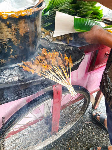 a street satay vendor who is cooking satay or Sate for customers