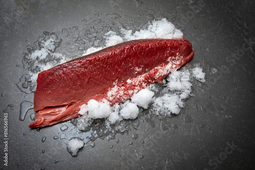 Large piece of ahi tuna on ice on a grey granite surface