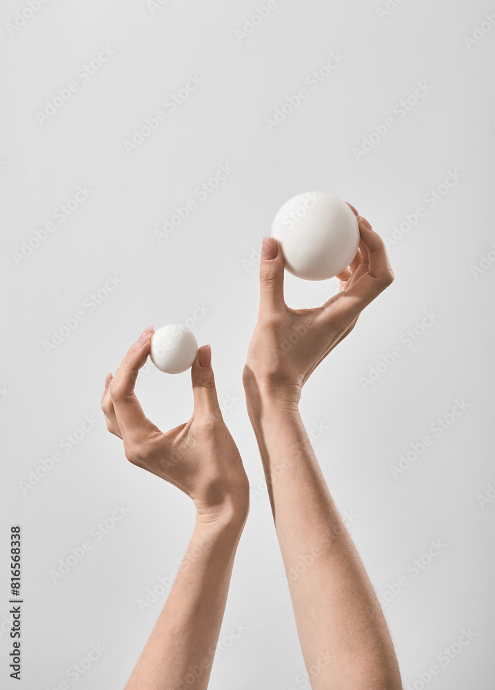 Female hands Holding two balls of different Sizes On a simple background Female hands Holding two balls of different Sizes On a simple background