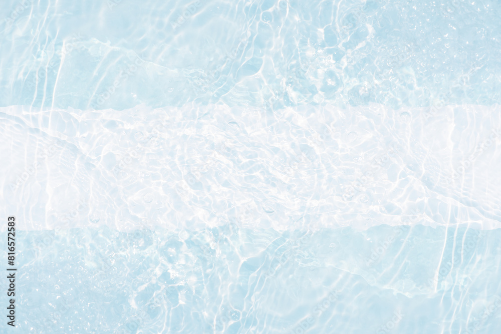 Obraz premium Blue water with ripples on the surface. Defocus blurred transparent blue colored clear calm water surface texture with splashes and bubbles. Water waves with shining pattern texture background.
