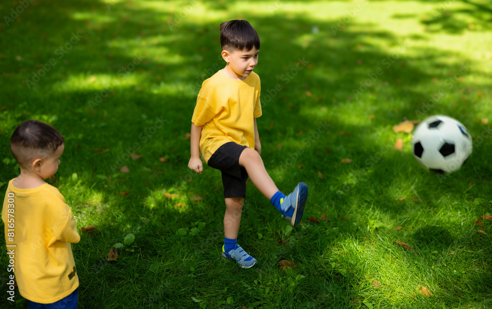 boy kid playing football in park on grass.child with ball in hands lying on ground.siblings, brothers and father,dad and son,playing together. balloon under man arm.getting ready for championship boy kid playing football in park on grass.child with ball in hands lying on ground.siblings, brothers and father,dad and son,playing together. balloon under man arm.getting ready for championship