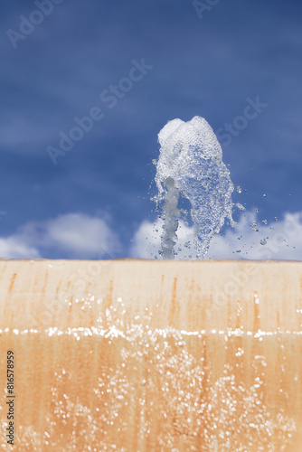 stream of water coming out of a public fountain with a blue sky in the background