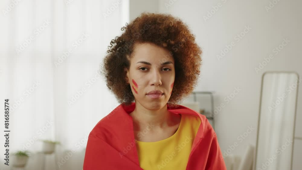 Calm woman Spanish sport fan cheering for favorite Spain team, with painted flag on cheeks. European and World football, 2026 USA, Canada, Mexico. Football, Sports and soccer fans. Slow Motion