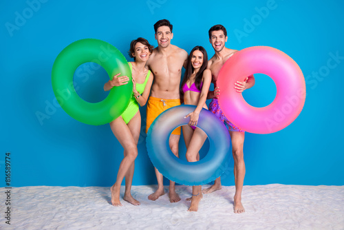 Full length photo of charming cute fellows company wear swimsuits going swim circles isolated blue color background