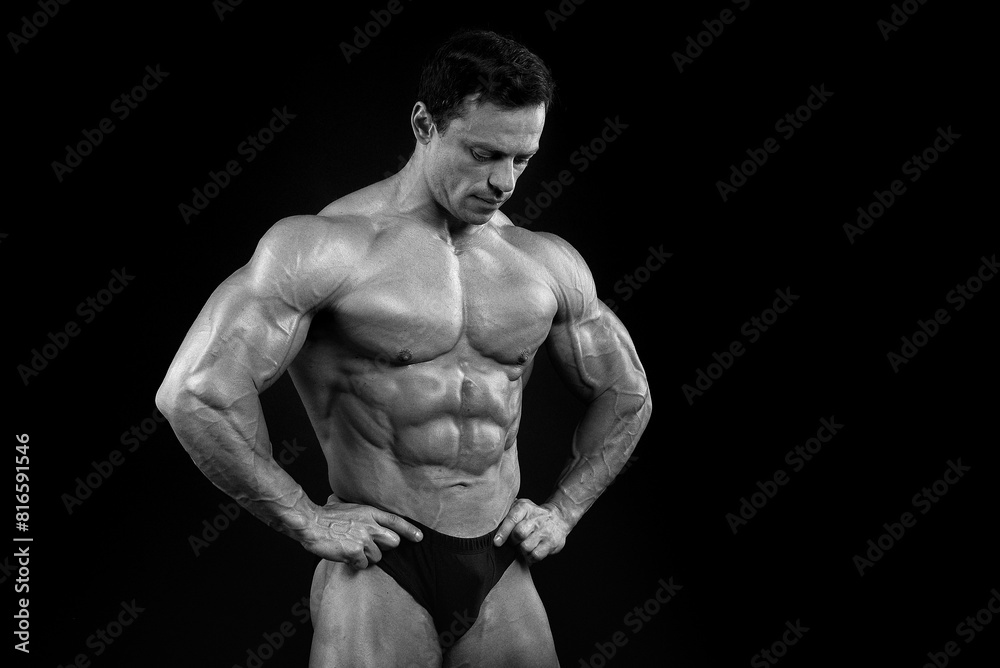 Fototapeta premium Athlete bodybuilder posing for a sports magazine in the studio on a black background. Grain effect used