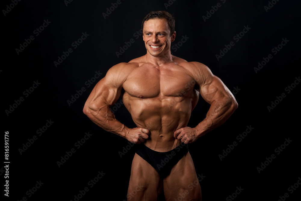 Athlete bodybuilder posing for a sports magazine in the studio on a black background. Grain effect used Athlete bodybuilder posing for a sports magazine in the studio on a black background. Grain effect used