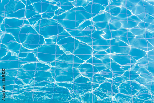 Blue swimming pool water surface and ripple wave background. Summer abstract reflection caustics in swimming pool.