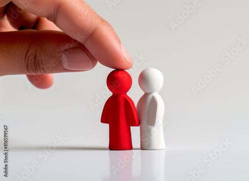 Hand placing red figurine next to white figurine, matchmaking concept. photo