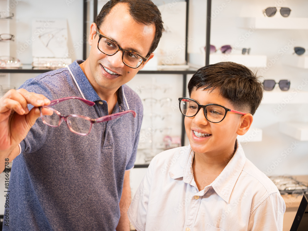 Happy Indian father and cute son choosing eyeglasses in an optics store.. Happy Indian father and cute son choosing eyeglasses in an optics store..