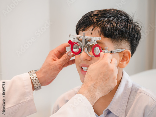 India cute boy sitting in an eyeglass shop with an optometrist specializing in eye disorders and primary eye health looking for a lens to suit his eyesight and get the most effective eyeglasses.