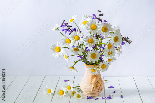 Beautiful bouquet of daisies flowers in a vase on a white wooden table
