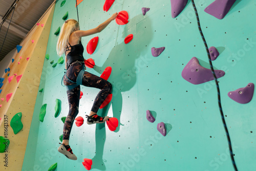 at the climbing wall young girl climbs the wall for the first time, the coach belays with a safety rope