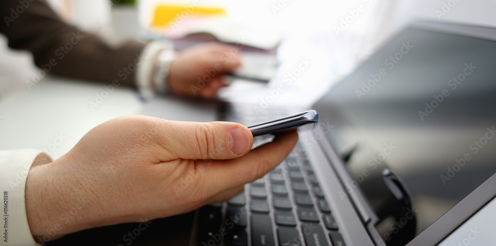 Male arms hold credit card press buttons making transfer closeup. Anti-fraud financial security when entering client discount program number or filling personal credential password login to account Male arms hold credit card press buttons making transfer closeup. Anti-fraud financial security when entering client discount program number or filling personal credential password login to account