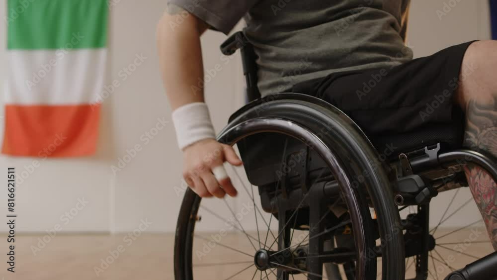 Tilt down shot of young Caucasian male basketball player with disability using protective finger bandages while getting ready for indoor training on court