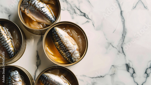 Opened tin cans with sprats in oil on white marble tabLE photo