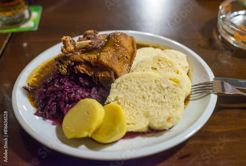 Roast duck with mashed potatoes, knedlíks and red cabbage on a white plate