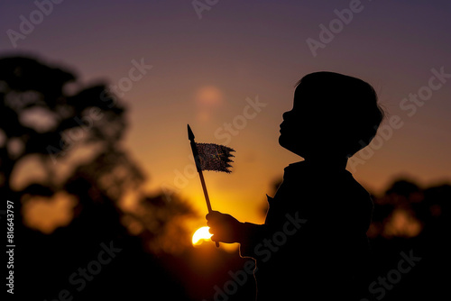 Backlit child-sized flag bearer's silhouette creates a dramatic Memorial Day dawn service scene.