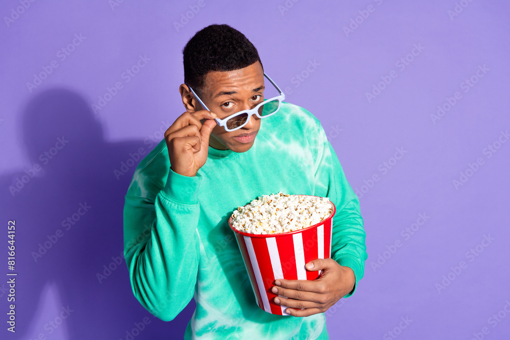 Photo of suspicious guy wear teal sweatshirt enjoy film eat pop corn look you isolated purple color background
