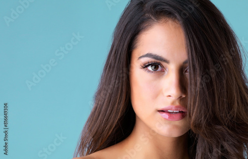 Beauty, makeup and portrait of woman in studio for cosmetics, confidence or facial glow on blue background. Salon, aesthetic and model with gloss lips for self care, satisfaction or cosmetology