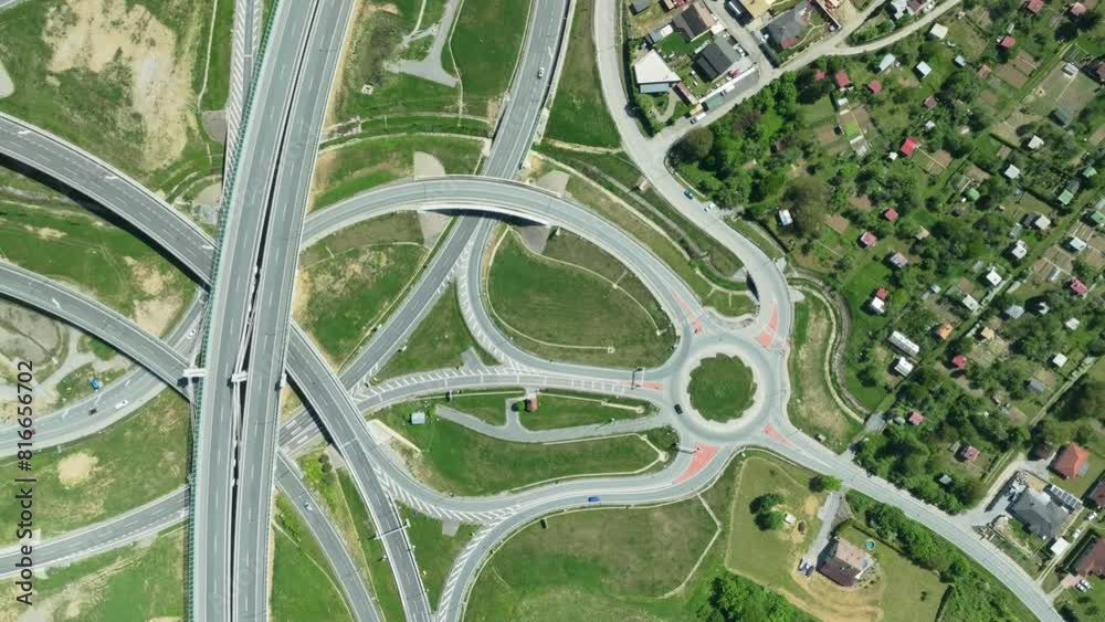 An aerial drone zoom-in shot captures intricate highway junction with cars navigating complex roundabouts and intersecting roads. Drone is moving down closer to the roads with cars. LuPa Creative.