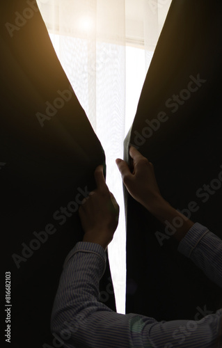 Woman is closing curtains near the window. Sunny day. Sunshine and warm at home.